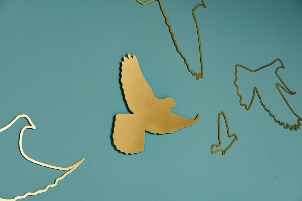 Middle Eight - Covent Garden - Preferred Hotels And Resorts London Bagian luar foto The photo shows a collection of metallic gold bird silhouettes against a solid turquoise background. The birds are depicted in various positions and styles, showcasing different species and flight postures. Some silhouettes are more detailed, while o