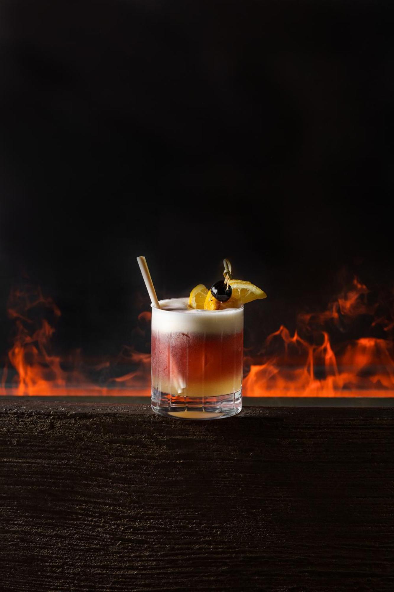 Middle Eight - Covent Garden - Preferred Hotels And Resorts London Bagian luar foto The image shows a cocktail presented in a clear glass with a thick base. The drink features layered colors, transitioning from a deep reddish hue at the bottom to a lighter, frothy layer on top. It is garnished with a slice of lemon and a cherry, and